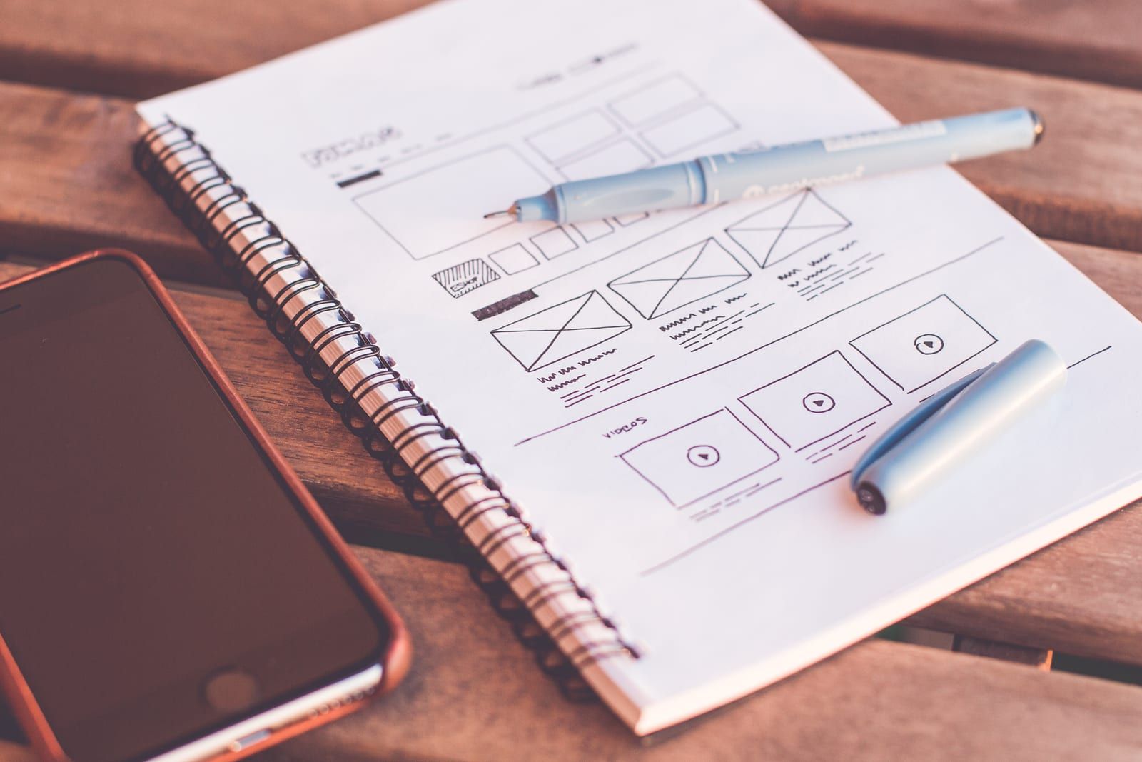 Wireframe sketches of a website layout in a notebook beside a phone